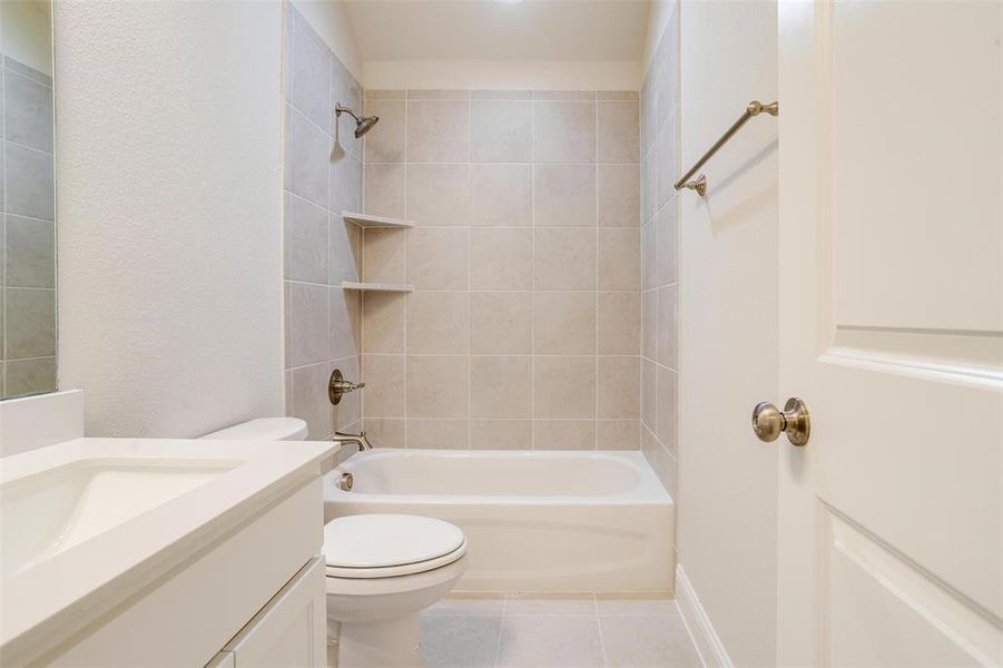 Full bathroom with tile patterned flooring, toilet, vanity, and tiled shower / bath