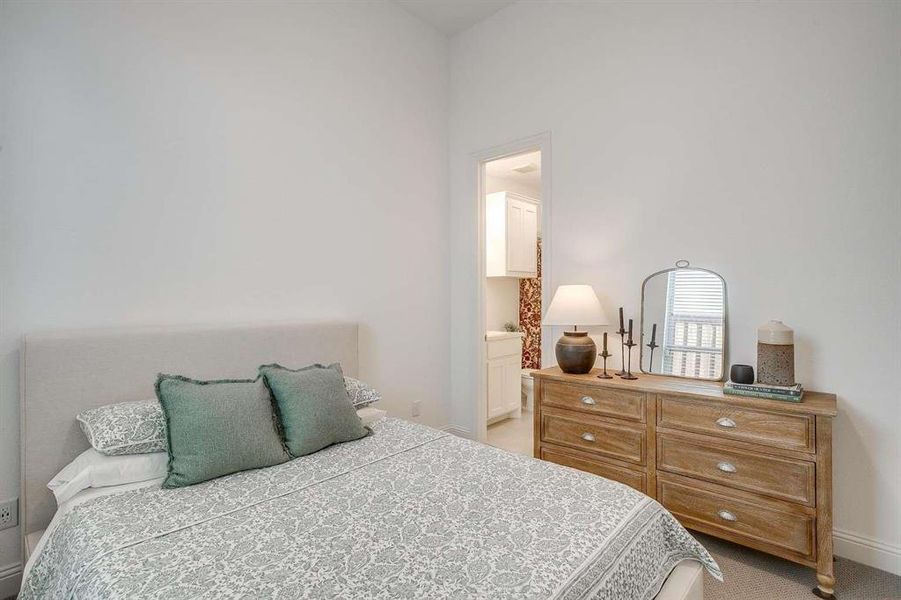 Bedroom with ensuite bathroom and light carpet