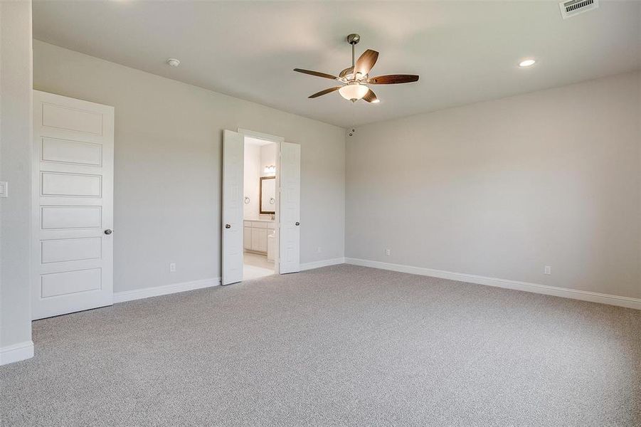 Unfurnished bedroom with connected bathroom, ceiling fan, and light colored carpet