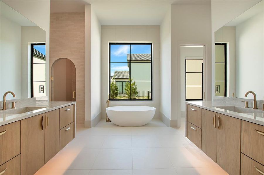 Primary Bathroom featuring a bathtub, a wealth of natural light, tile patterned flooring, and vanity