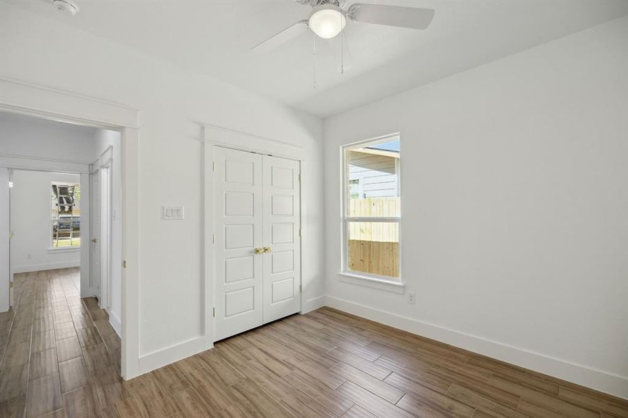 Unfurnished bedroom with a closet, ceiling fan, multiple windows, and light wood-type flooring