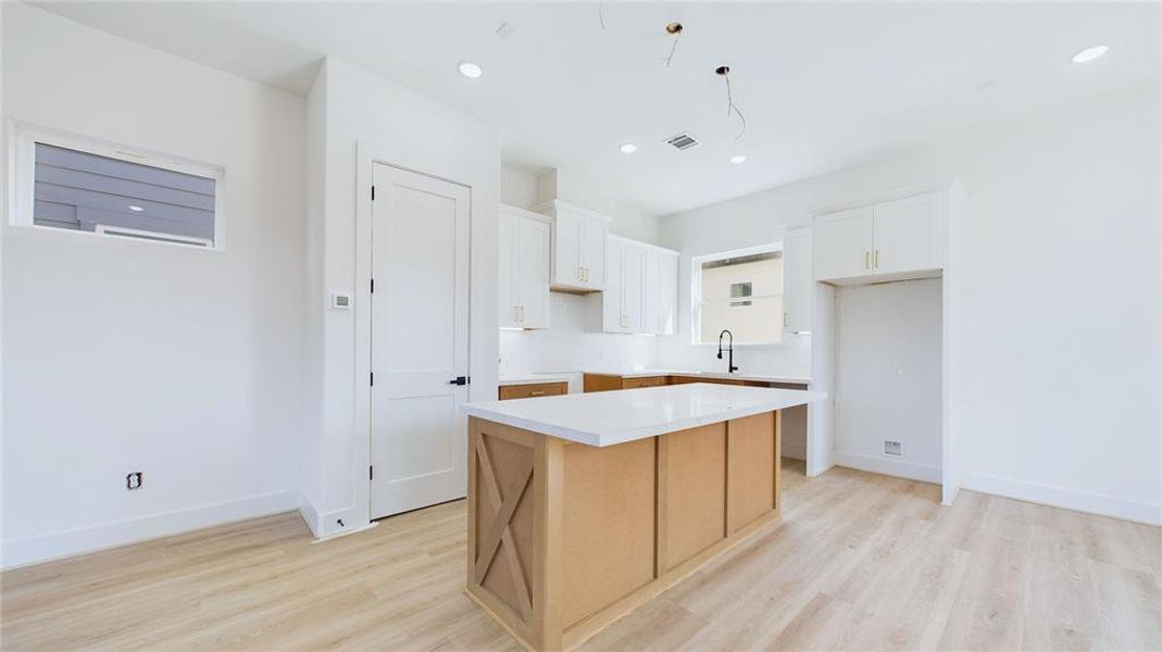 This alternate kitchen view showcases the expansive white countertops and abundant cabinetry, providing perfect storage for any chef. A generously sized pantry adds even more storage space.