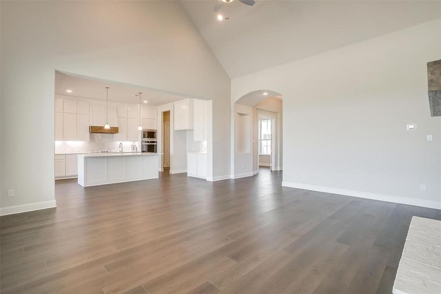 Unfurnished living room featuring sink, hardwood / wood-style flooring, high vaulted ceiling, and ceiling fan