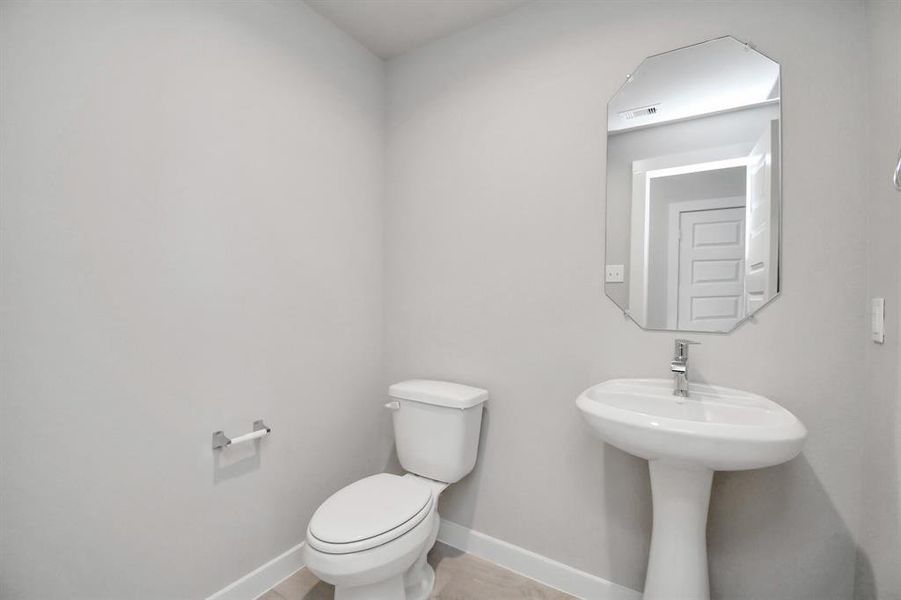 This half bathroom features a stylish pedestal sink, modern hardware, and bright recessed lighting, creating a sleek and inviting space.