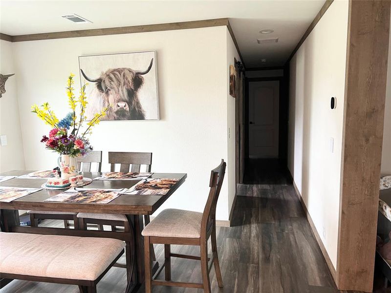 Dining area with dark wood-type flooring and crown molding