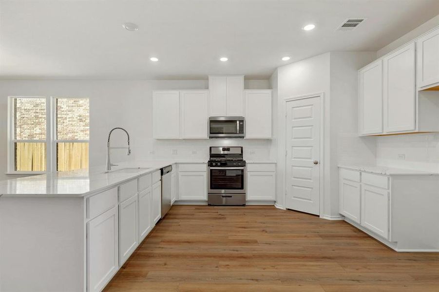 Beautiful kitchen with white cabinets, a huge countertop, a gas stove, and stainless steel appliances, ideal for everyday cooking and gatherings.