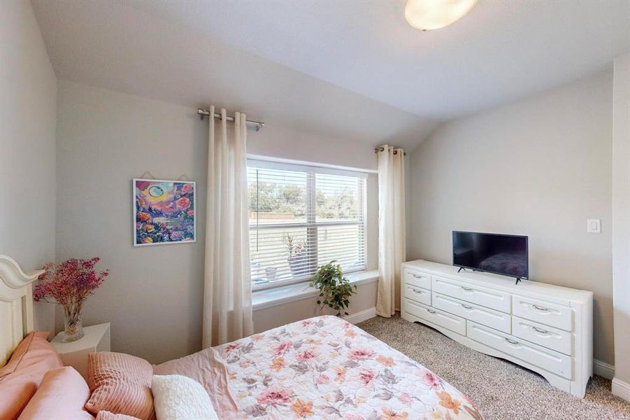 Bedroom with light carpet and vaulted ceiling