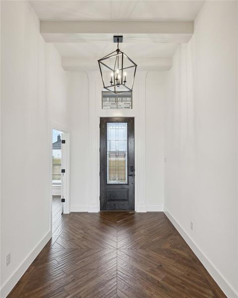 Entryway featuring dark parquet flooring, a chandelier, and beamed ceiling