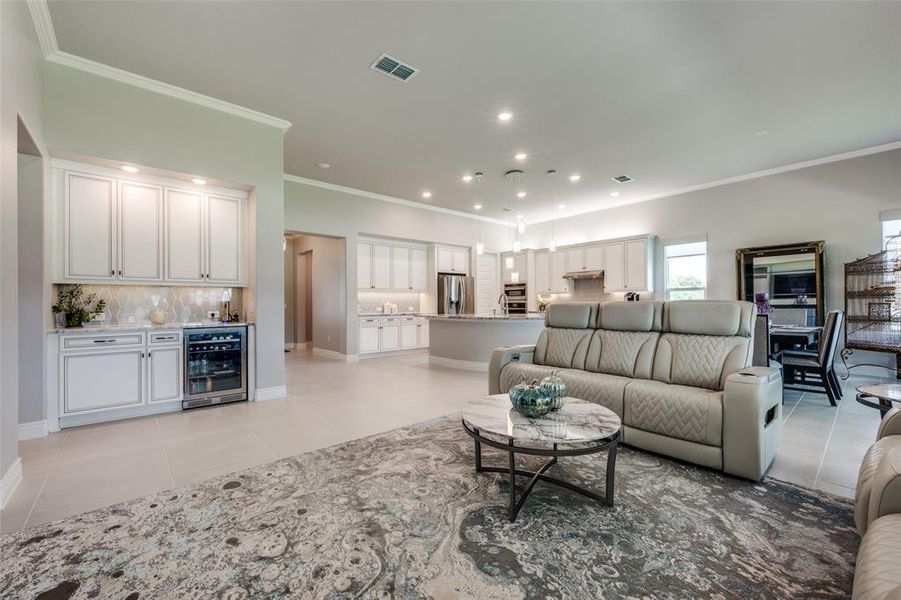 Tiled living room with ornamental molding, beverage cooler, and bar