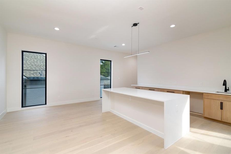 Kitchen with a center island, light hardwood / wood-style flooring, pendant lighting, sink, and light brown cabinetry