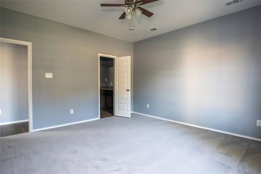 Unfurnished bedroom featuring dark carpet and ceiling fan