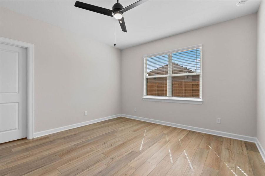 The primary bedroom features luxury vinyl plank flooring and a modern ceiling fan.