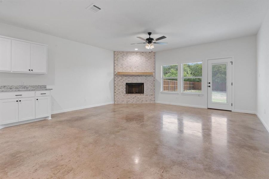 Unfurnished living room featuring ceiling fan and a large fireplace