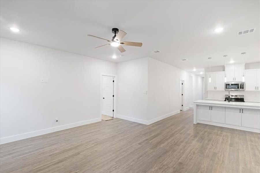 Unfurnished living room featuring light wood-type flooring and ceiling fan