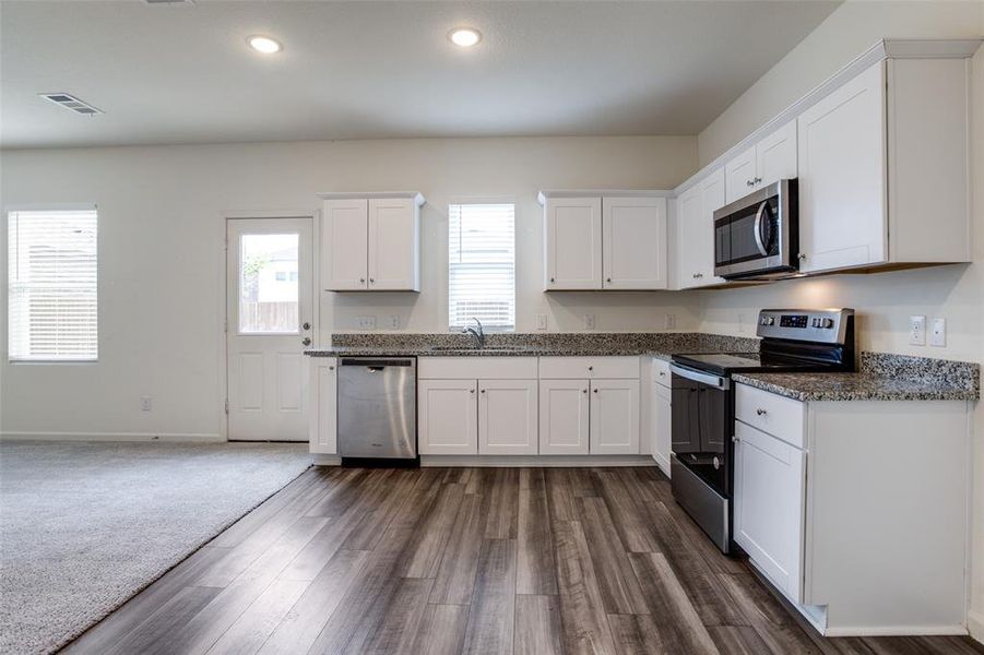 Kitchen featuring white cabinetry, dark carpet, appliances with stainless steel finishes, and sink