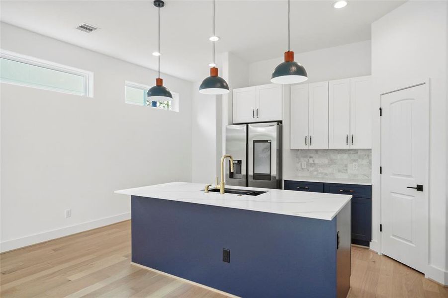 Stunning chef's kitchen featuring a striking blue island and sleek white countertops.