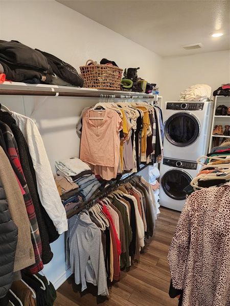 Spacious closet with stacked washer and clothes dryer and dark hardwood / wood-style floors