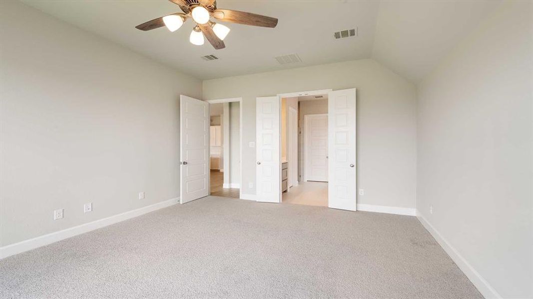 Unfurnished bedroom with light carpet, vaulted ceiling, and ceiling fan