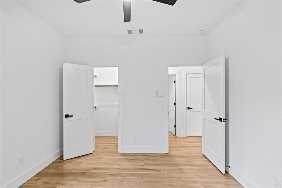 Unfurnished bedroom with ceiling fan, light wood-type flooring, a closet, and a spacious closet