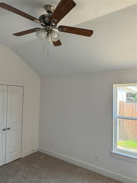 Another view of the 3rd  bedroom with carpet floors, ceiling fan, vaulted ceiling, and walkin closet