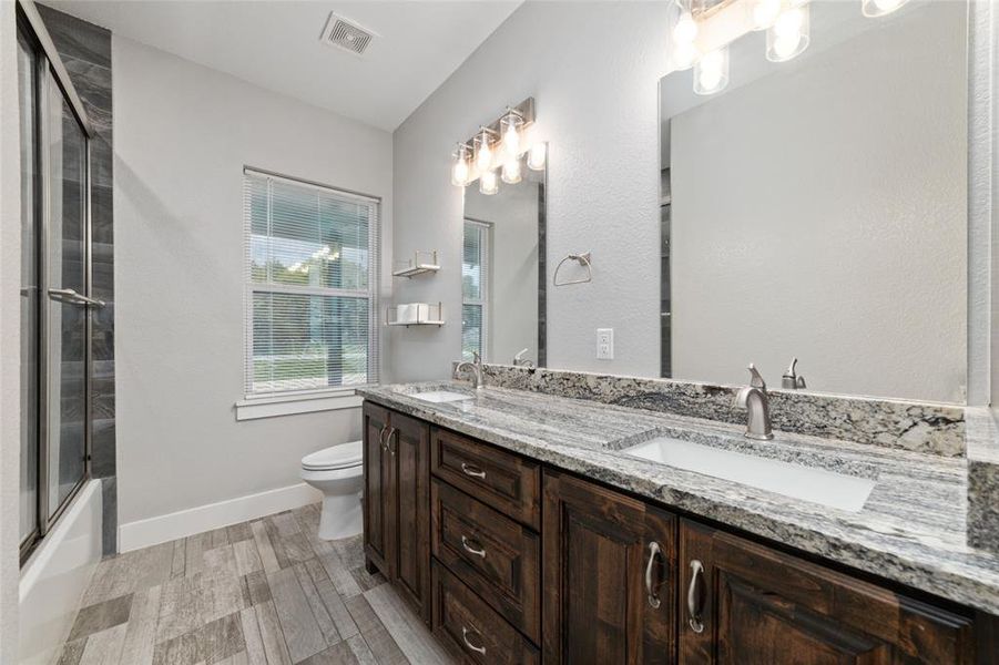 Step into the second bathroom, where you'll find a spacious double vanity sink that's perfect for busy mornings. The sleek tile flooring adds a touch of elegance, complemented by two large mirrors illuminated by overhead lighting, ensuring you always look your best. Relax in the tub/shower combo enclosed by a sliding glass door, offering both convenience and style.