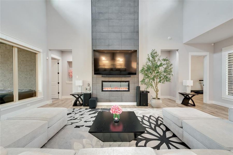 Living room featuring light hardwood / wood-style flooring, a tiled fireplace, and a high ceiling