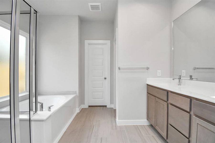 Indulge in a spa-like retreat within the confines of this primary bathroom. Photo shown is example of completed home with similar plan. Photo shown is example of completed home with similar plan.