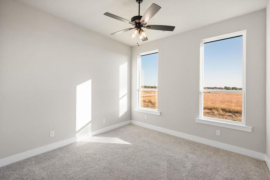 Spare room with a healthy amount of sunlight, light colored carpet, and ceiling fan