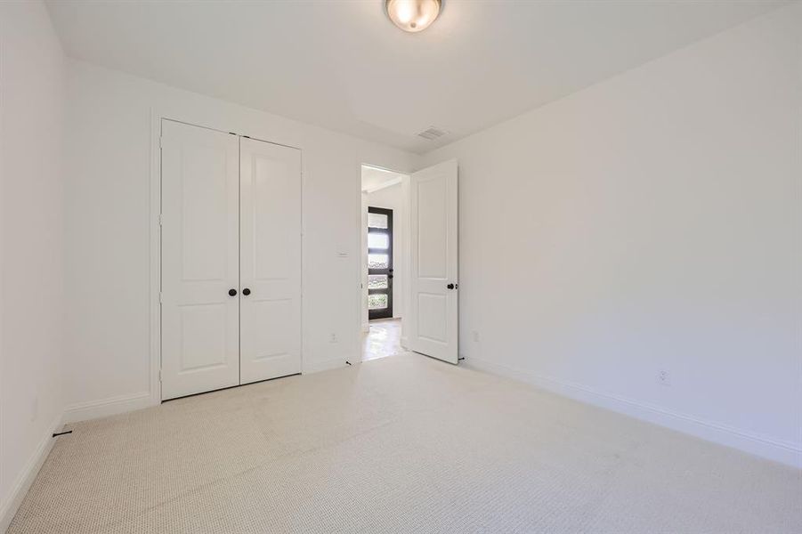 Unfurnished bedroom featuring light carpet and a closet