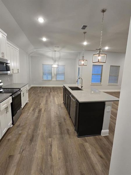 Kitchen featuring white cabinets, appliances with stainless steel finishes, dark hardwood / wood-style flooring, sink, and a center island with sink