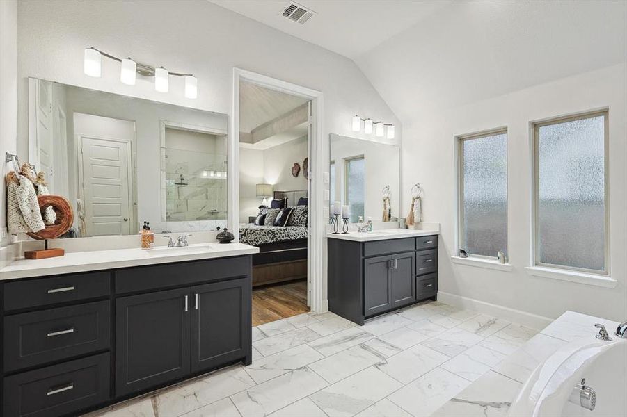 Bathroom featuring vaulted ceiling, shower with separate bathtub, and vanity