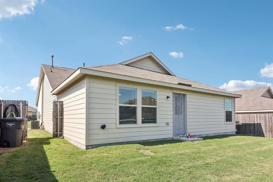 Back of house featuring cooling unit and a lawn