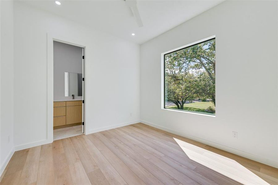 Unfurnished bedroom with light wood-type flooring, ceiling fan, and ensuite bathroom