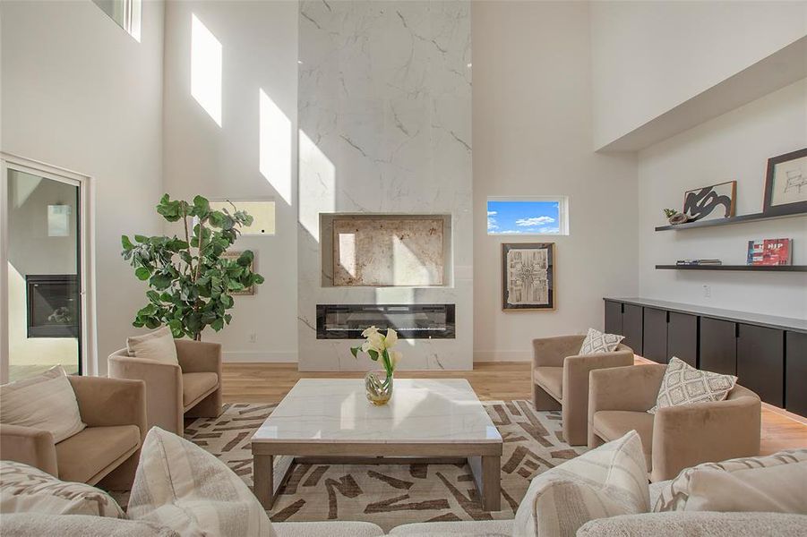 Living room with a high ceiling, light hardwood / wood-style flooring, and a fireplace