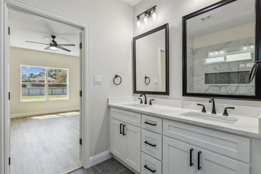 Bathroom featuring ceiling fan, vanity, tile patterned flooring, and a tile shower