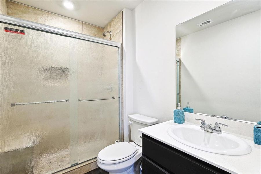 Bathroom with vanity, toilet, and an enclosed shower