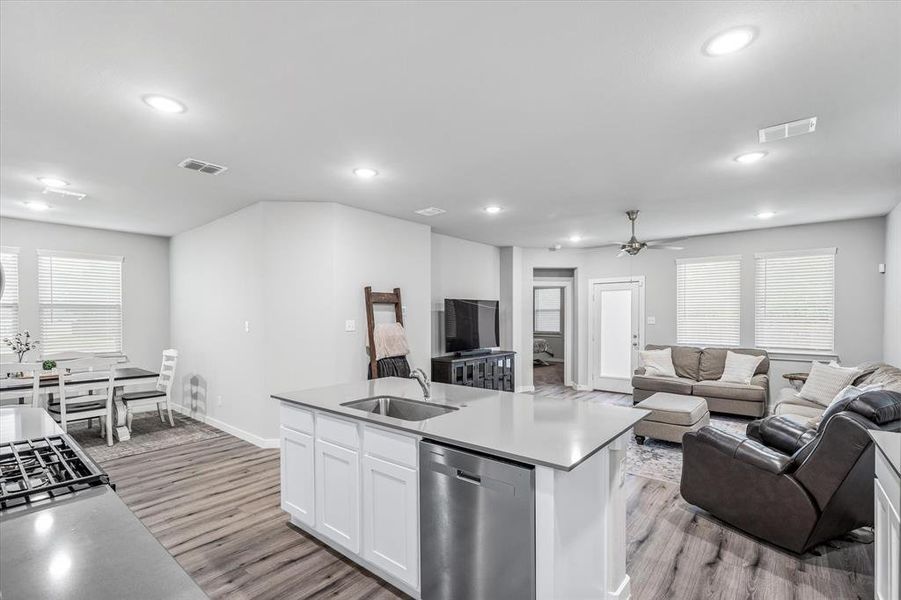 Kitchen with light hardwood / wood-style flooring, an island with sink, white cabinets, sink, and dishwasher