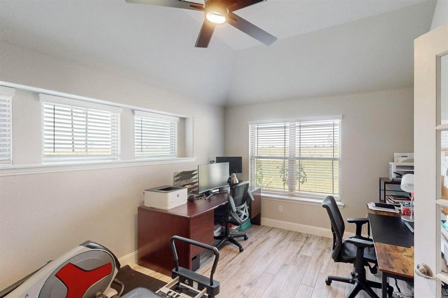 Office area featuring light wood-type flooring, ceiling fan, and vaulted ceiling