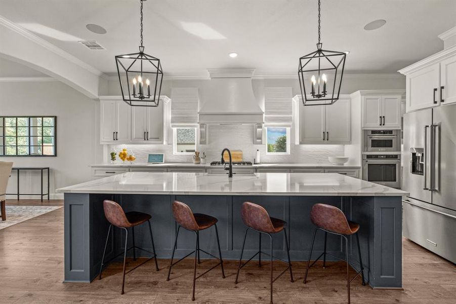 Kitchen featuring a large island with sink, white cabinetry, stainless steel appliances, and hardwood / wood-style flooring