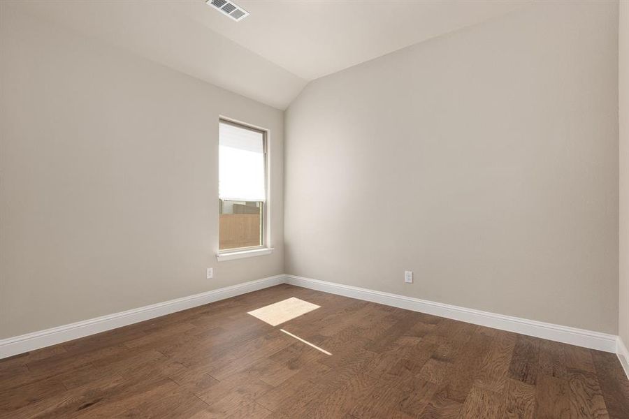 Empty room with vaulted ceiling and dark hardwood / wood-style flooring