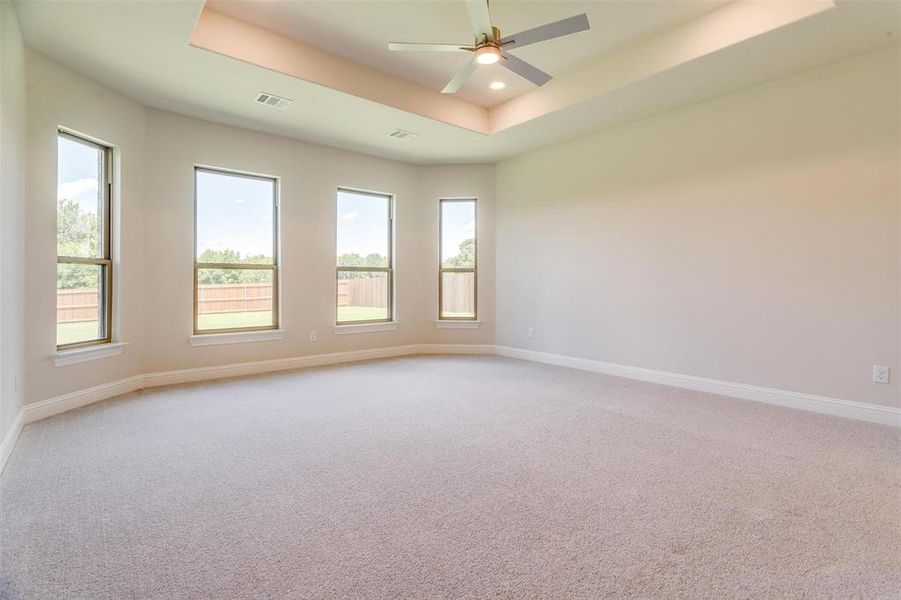 Carpeted empty room with a raised ceiling and ceiling fan