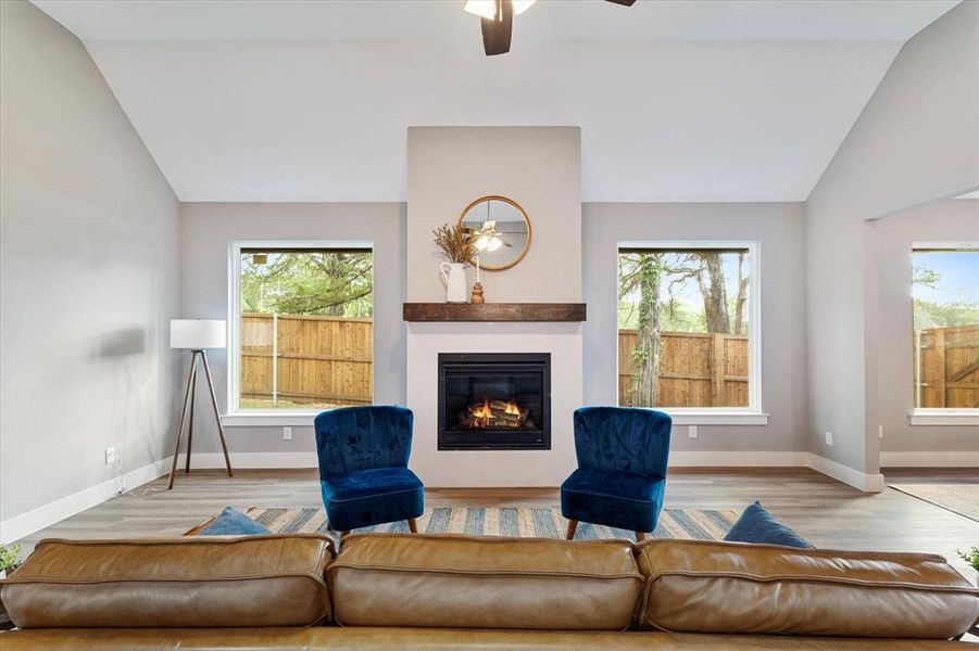 Living room with ceiling fan, vaulted ceiling, and hardwood / wood-style floors