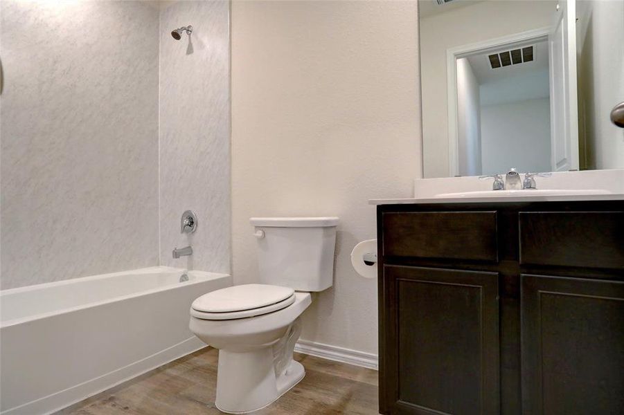 Full bathroom featuring vanity, shower / bath combination, hardwood / wood-style floors, and toilet