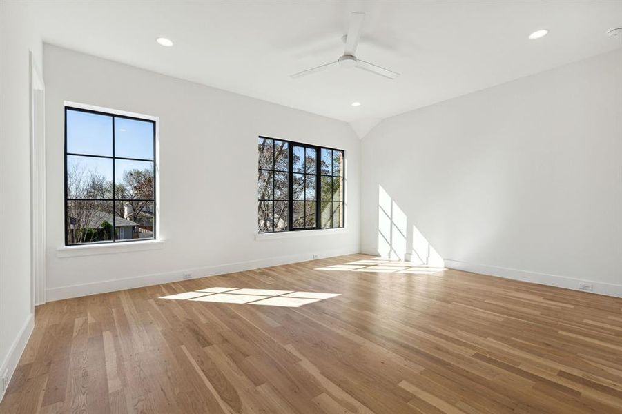 Lots of light in this secondary bedroom featuring light wood and a ceiling fan