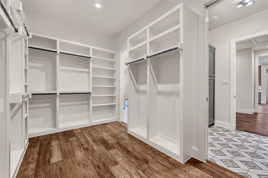 Primary closet boasts custom shelves and wood floors