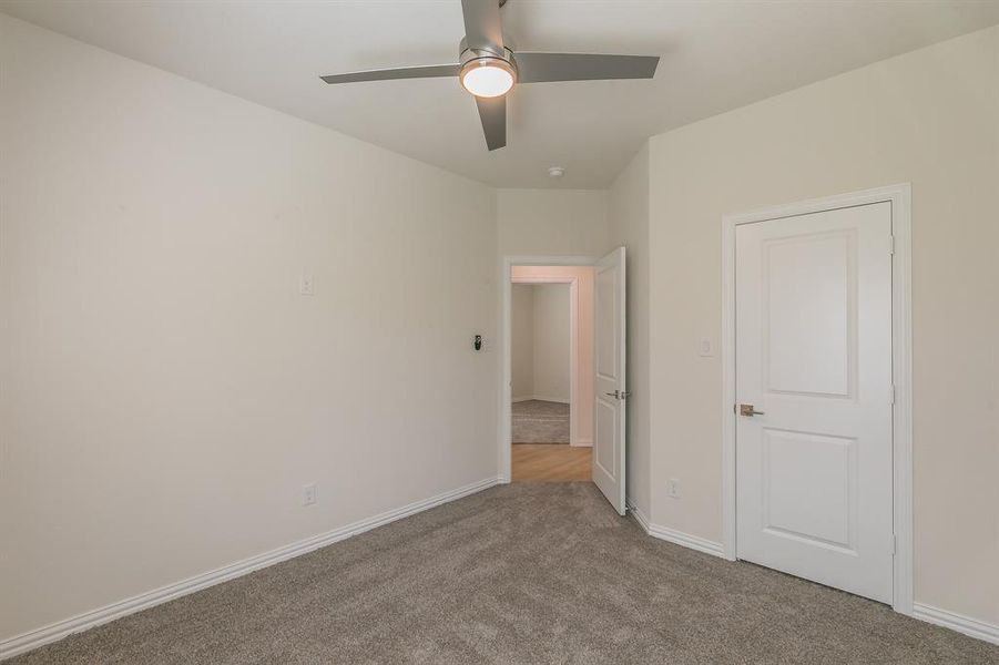 Unfurnished bedroom featuring ceiling fan and light colored carpet