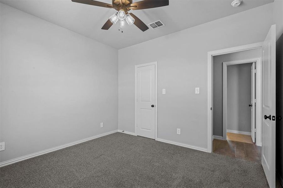 Unfurnished bedroom with dark carpet and ceiling fan