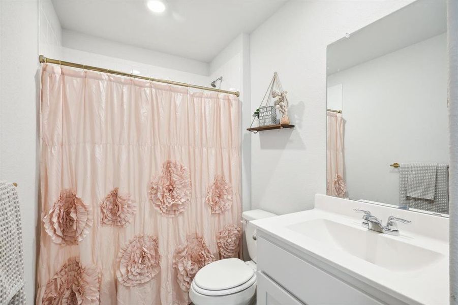 Bathroom featuring curtained shower, vanity, and toilet