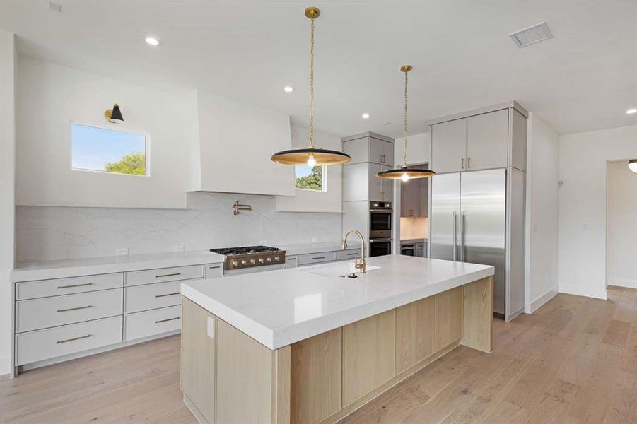 Kitchen with a healthy amount of sunlight, a center island with sink, sink, and decorative light fixtures