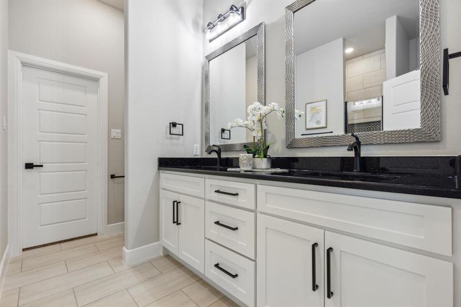 Bathroom featuring dual sinks, tile flooring, and vanity with extensive cabinet space